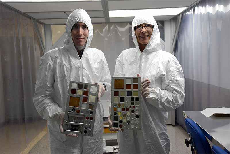 Aegis Employees suited up in a clean room holding MISSE testing samples