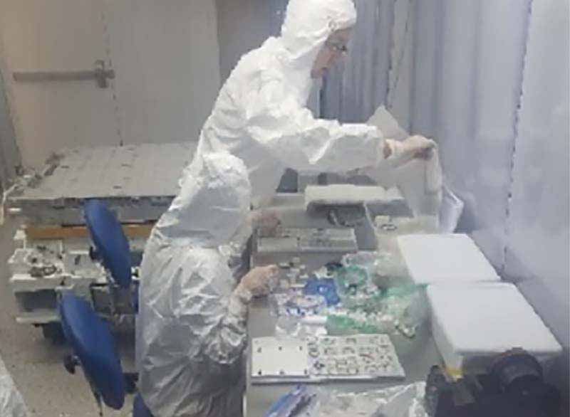 workers in bunny suits assembling items in a clean room